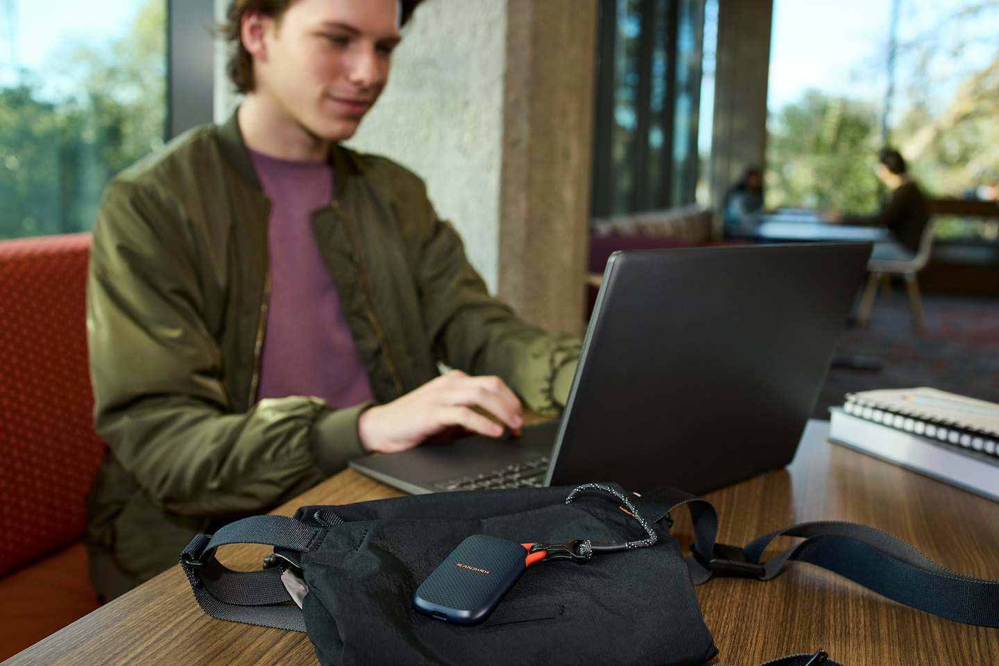 Persona trabaja en un portátil en una mesa de cafetería.
