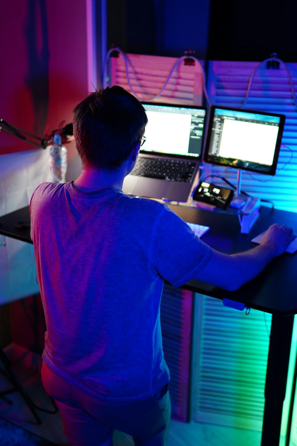 Persona trabajando en un escritorio con portátil y monitor.